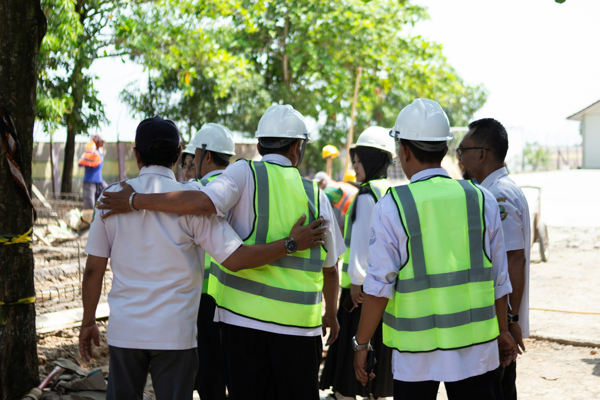 Construction workers in hard hats and vests huddle together